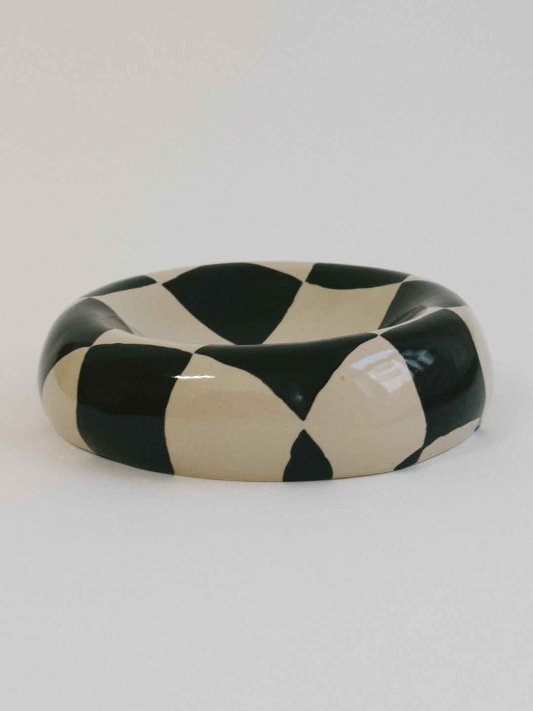 Handgeformter Keramikteller von Zoe Deno. Gefertigt in Wien. Material: Ton, glasiert. Bemalt in Schwarz und Beige im Schachbrettmuster. Jedes Stück ist ein Unikat. Als Wandobjekt oder Tellerskulptur nutzbar.
